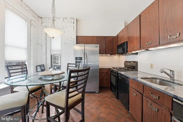 a kitchen with stainless steel appliances granite countertop a sink a stove a refrigerator cabinets and chairs