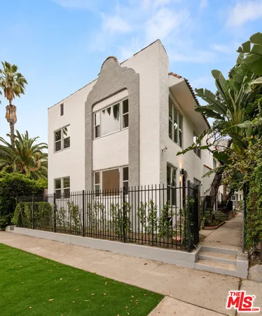 a view of a white house with a small yard and potted plants