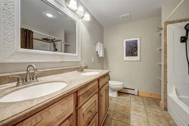 a bathroom with a granite countertop sink a toilet and a mirror