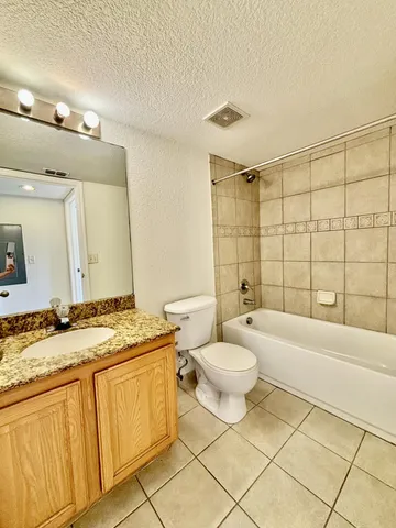 a bathroom with a granite countertop sink a toilet a mirror and bathtub