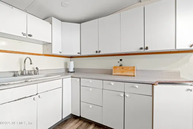 a kitchen with white cabinets and sink
