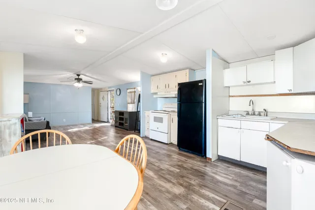 a kitchen with a refrigerator a stove top oven a sink dishwasher with a dining table and chairs