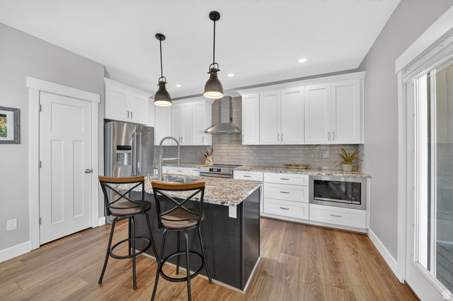 7872 Farm House Lane Midvale, UT 84047 - Photo 13 of 39 Kitchen featuring wood-finish flooring, white cabinetry, recessed lighting, and a kitchen island with pendant lighting