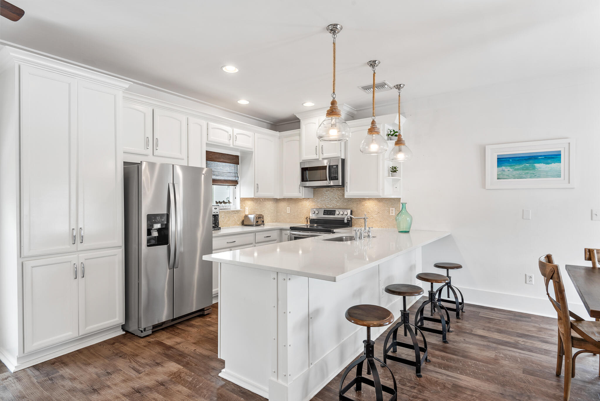 139 Brown Street Santa Rosa Beach, FL 32459 - Photo 17 of 45 a kitchen with kitchen island a refrigerator a stove a dining table and chairs with wooden floor