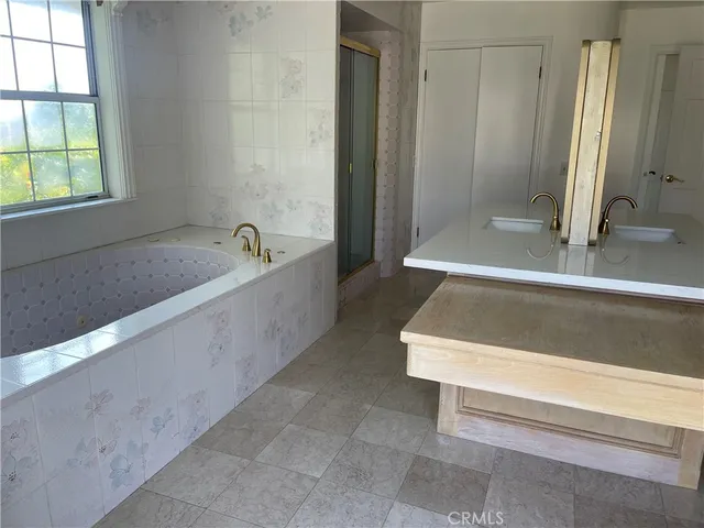 a bathroom with a tub a mirror and a shower