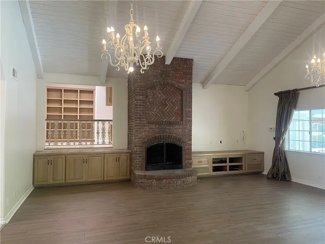 a view of a livingroom with a fireplace a chandelier and windows