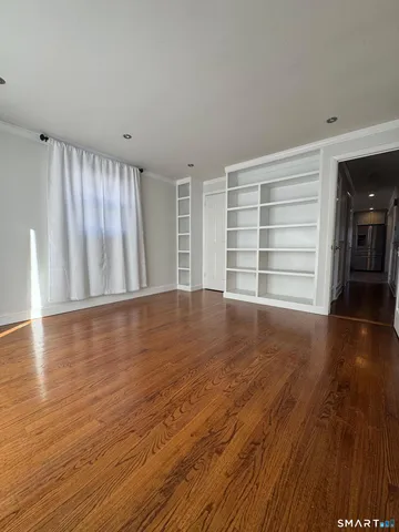a view of an empty room with a window and wooden floor