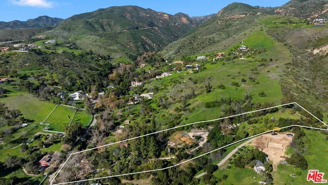 an aerial view of a houses with a lush green hillside