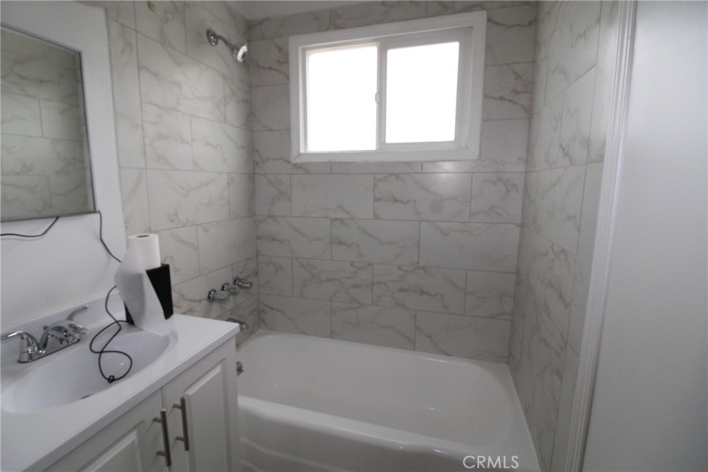 4954 Tweedy Boulevard, Unit F South Gate, CA 90280 - Photo 8 of 12 a bathroom with a bathtub sink vanity and window