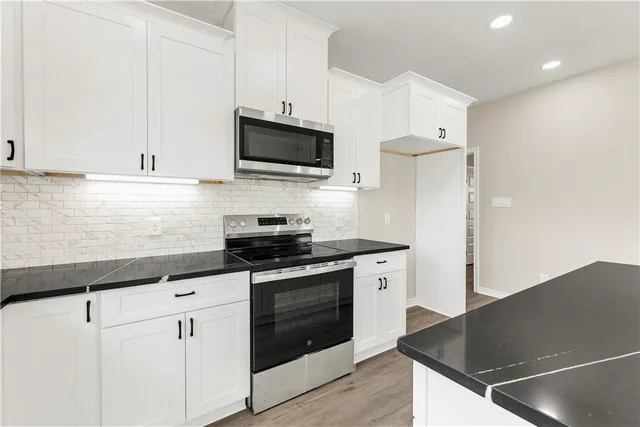 a large kitchen with stainless steel appliances kitchen island granite countertop a sink and a white cabinets