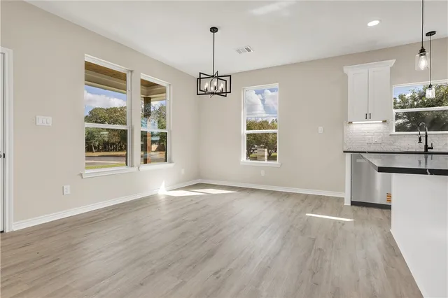 a view of an empty room with window and wooden floor