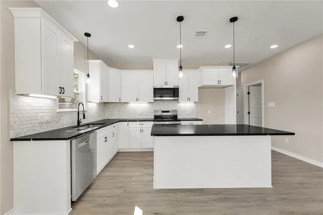 a kitchen with stainless steel appliances granite countertop a sink a stove a refrigerator and island with wooden floor