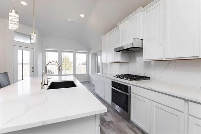 a kitchen with stainless steel appliances granite countertop a sink stove and cabinets