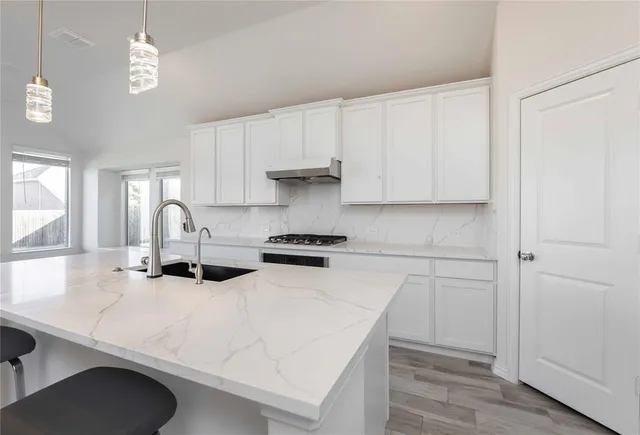 a kitchen with stainless steel appliances a white table chairs and a refrigerator