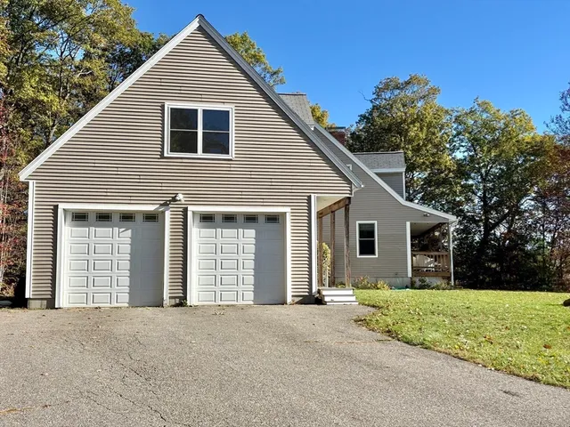 a front view of house with yard and trees in the background