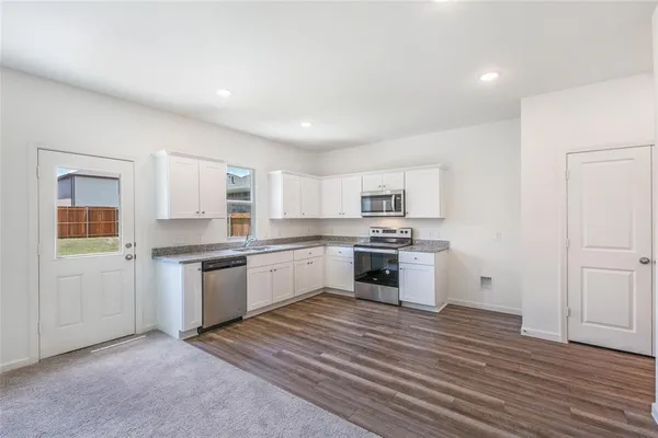 a kitchen with granite countertop a sink cabinets stainless steel appliances and a window