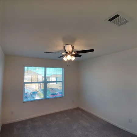 an empty room with windows and chandelier fan