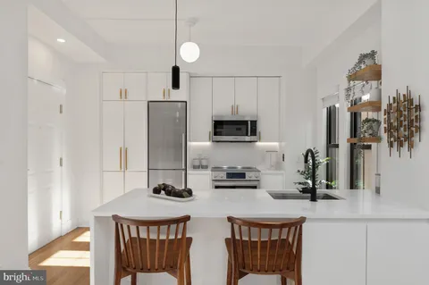 a kitchen with stainless steel appliances a sink a stove a refrigerator cabinets and a dining table