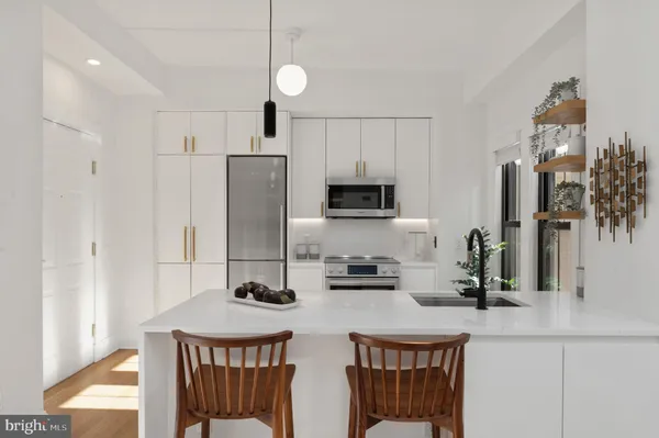 a kitchen with stainless steel appliances a sink a stove a refrigerator cabinets and a dining table
