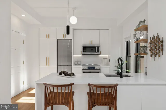 a kitchen with stainless steel appliances a sink a stove a refrigerator cabinets and a dining table