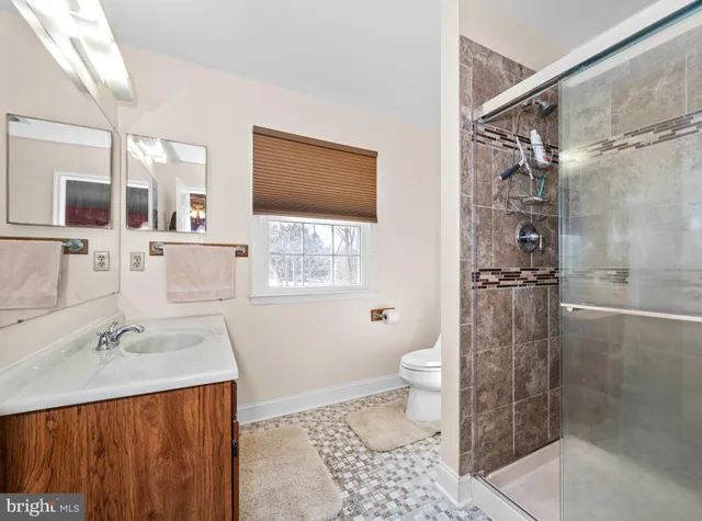 a bathroom with a granite countertop sink toilet a large mirror and a window