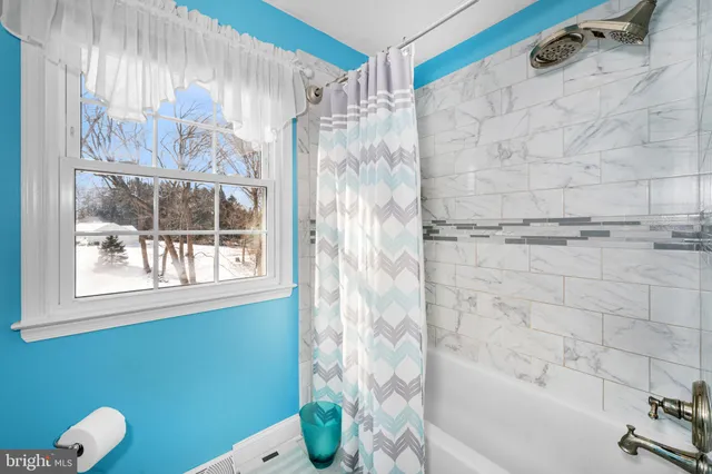 a bedroom with a bed chair and two windows