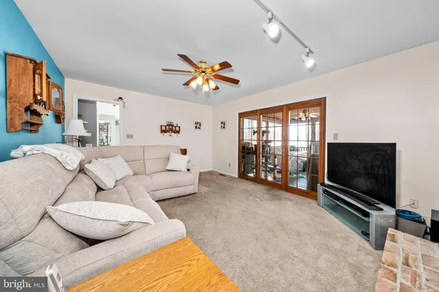 a living room with furniture a ceiling fan and a flat screen tv