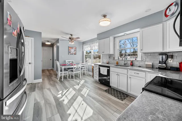 a kitchen with a sink dishwasher a stove a microwave oven and a dining table with wooden floor