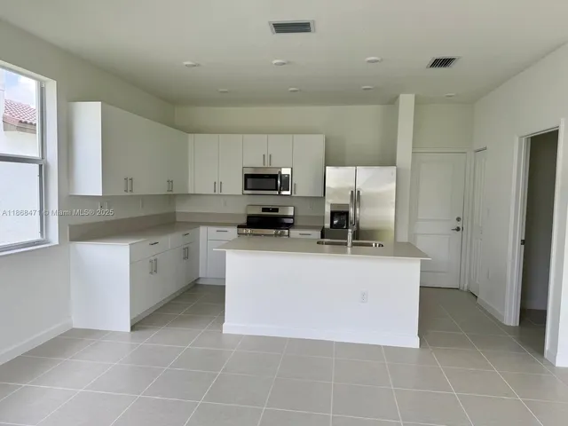 a kitchen with stainless steel appliances a sink a stove a microwave a sink a refrigerator and cabinets