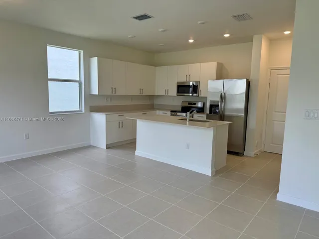 a kitchen with stainless steel appliances a sink a stove a refrigerator cabinets and a window