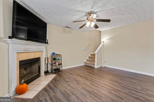 a view of a livingroom with wooden floor a flat screen tv and a fireplace