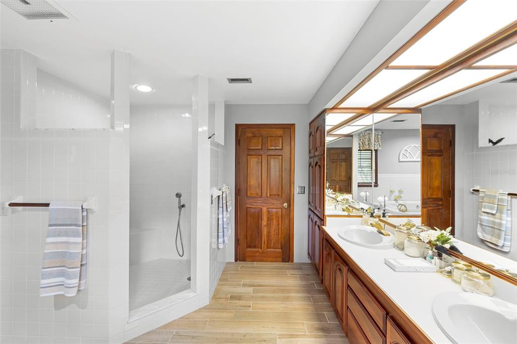 1056 Reynolds Road De Leon Springs, FL 32130 - Photo 27 of 74 a bathroom with a double vanity sink a large mirror and a bathtub