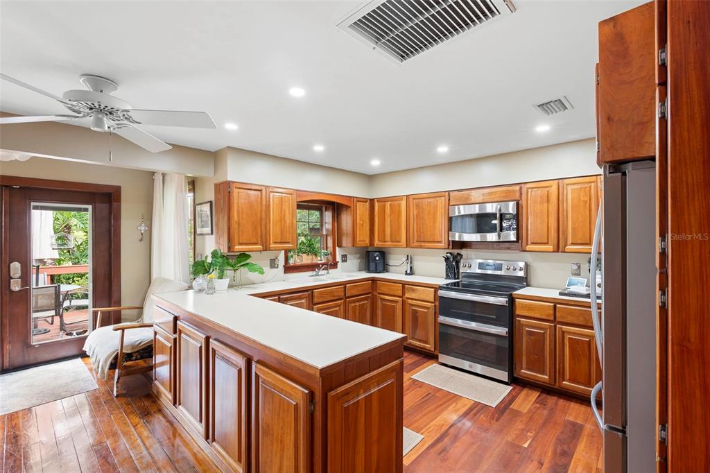 1056 Reynolds Road De Leon Springs, FL 32130 - Photo 28 of 74 a kitchen with stainless steel appliances a stove a sink dishwasher and a refrigerator with wooden floor