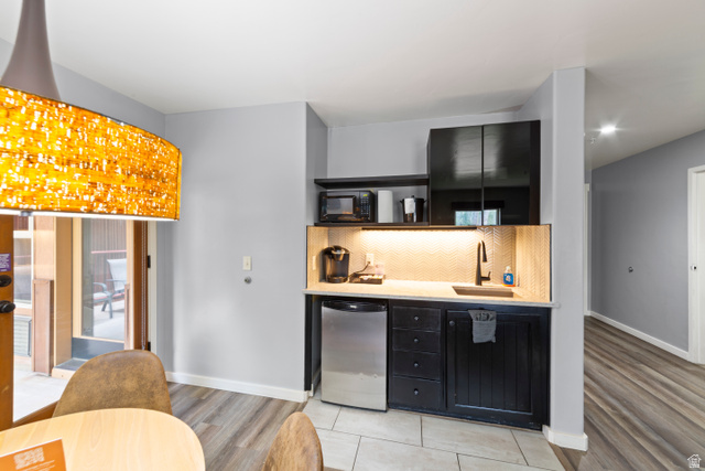 100 West 200 South, Unit 118 Moab, UT 84532 - Photo 13 of 39 Bar featuring dark cabinets, stainless steel refrigerator, light wood-style floors, black microwave, and light stone counters
