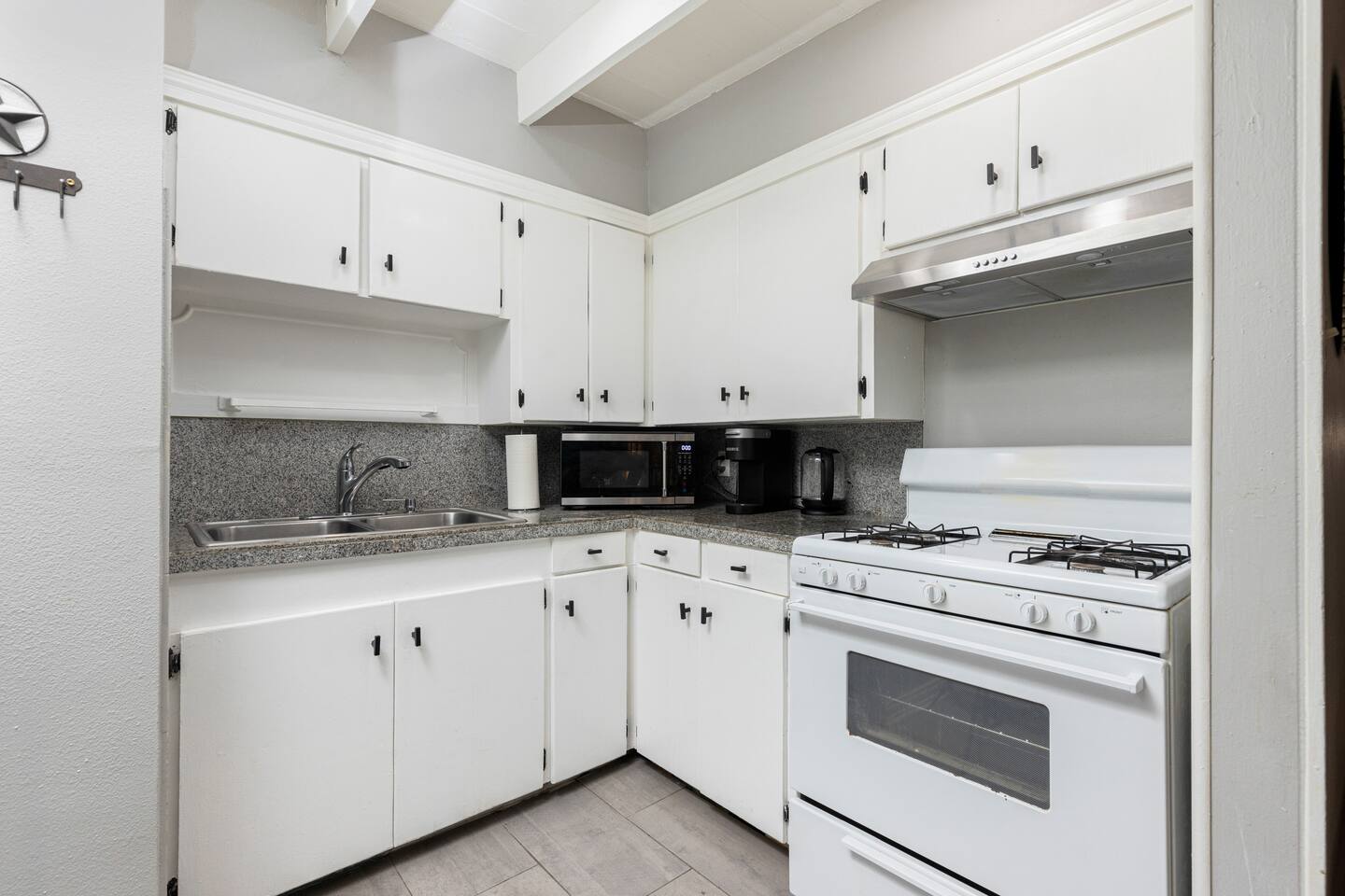 211 Lessin Lane, Unit B Austin, TX 78704 - Photo 11 of 18 Kitchen featuring white range with gas stovetop, decorative backsplash, white cabinetry, stainless steel microwave, and light wood-type flooring
