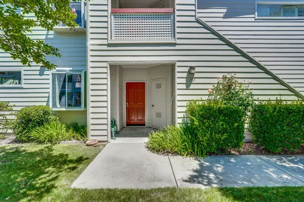 a front view of a house with a yard and potted plants