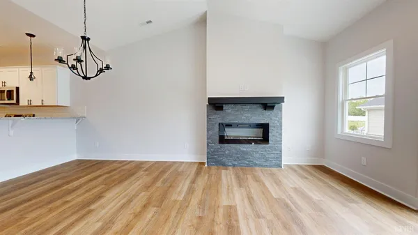 a view of a room with wooden floor and kitchen view