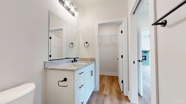 a bathroom with a granite countertop sink a toilet a mirror and shower