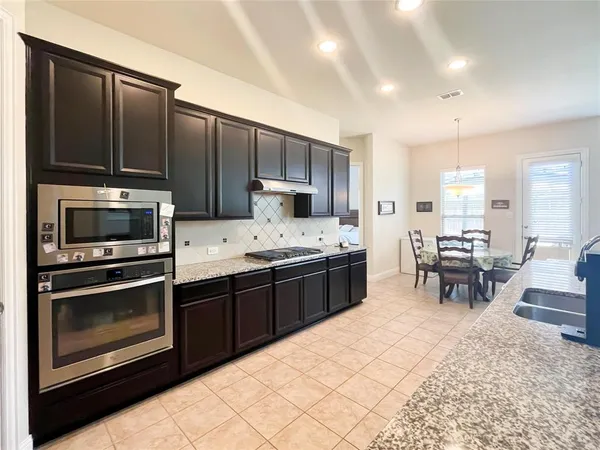 a kitchen with stainless steel appliances a stove a sink a microwave and chairs