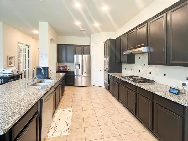 a large kitchen with granite countertop a large counter top stainless steel appliances and cabinets