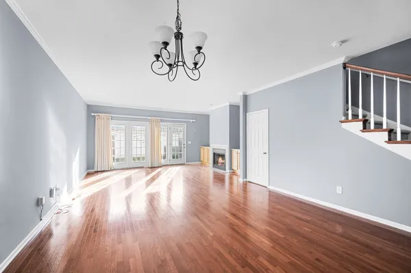 a view of an empty room with wooden floor and window