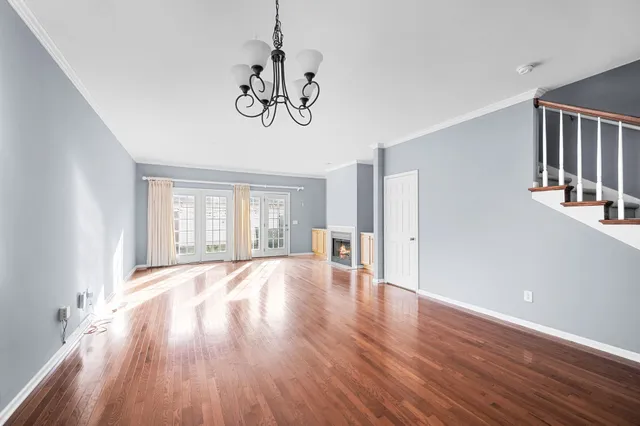 a view of an empty room with wooden floor and window