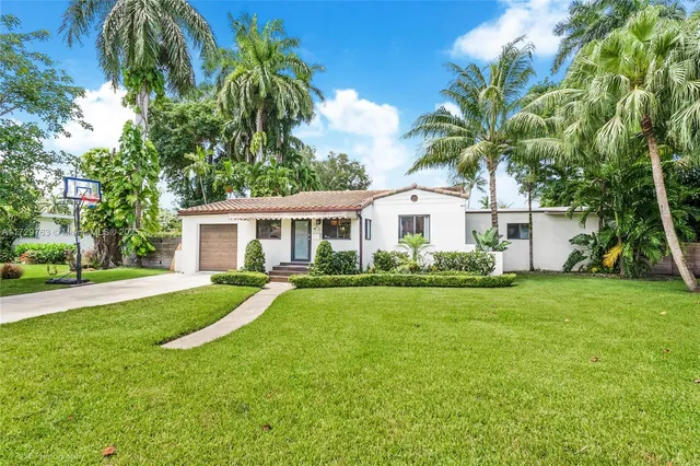 a view of a house with a yard and palm trees