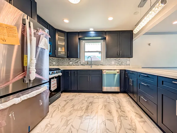 a large kitchen with stainless steel appliances granite countertop a stove sink and cabinets