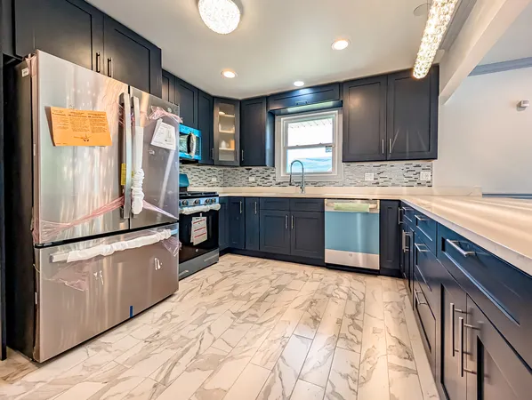 a kitchen with stainless steel appliances granite countertop a refrigerator a sink dishwasher a stove with white cabinets and wooden floor