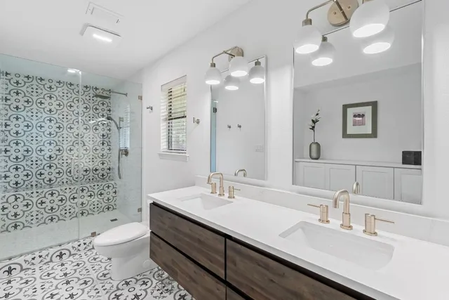a bathroom with a double vanity sink toilet and shower