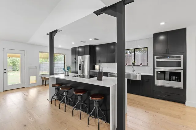 a kitchen with stainless steel appliances kitchen island granite countertop a table chairs sink and cabinets