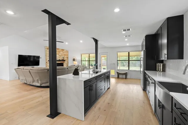 a large kitchen with stainless steel appliances a large counter top a sink a stove and a refrigerator