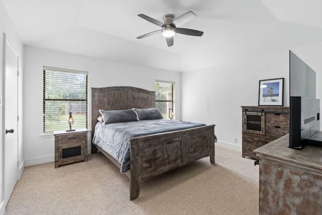 a bedroom with a bed dresser and a flat tv screen