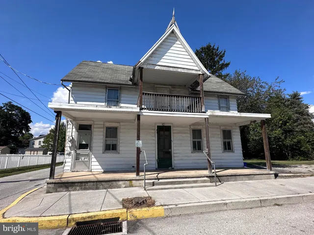 a view of a white house with large windows and a table and chairs